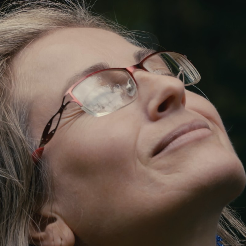 Eine ca. 40jährige Frau mit Brille neigt mit geschlossenen Augen ihren Kopf schräg nach oben.